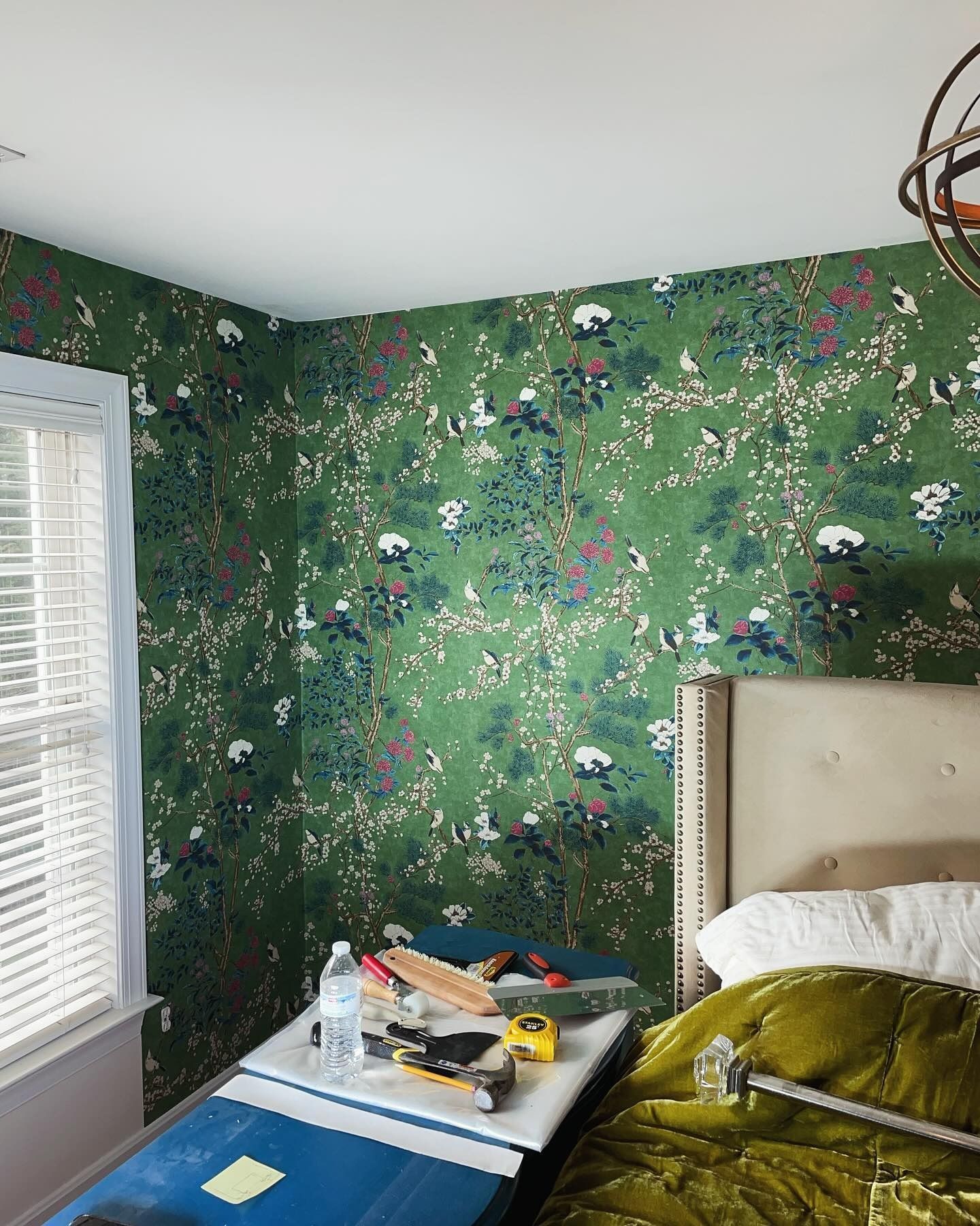 A bedroom with green floral wallpaper and a bed.