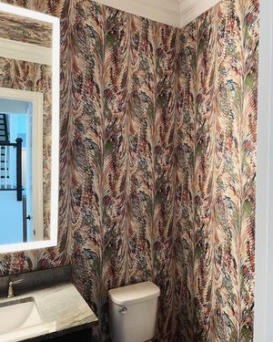 A bathroom with a toilet , sink and mirror.