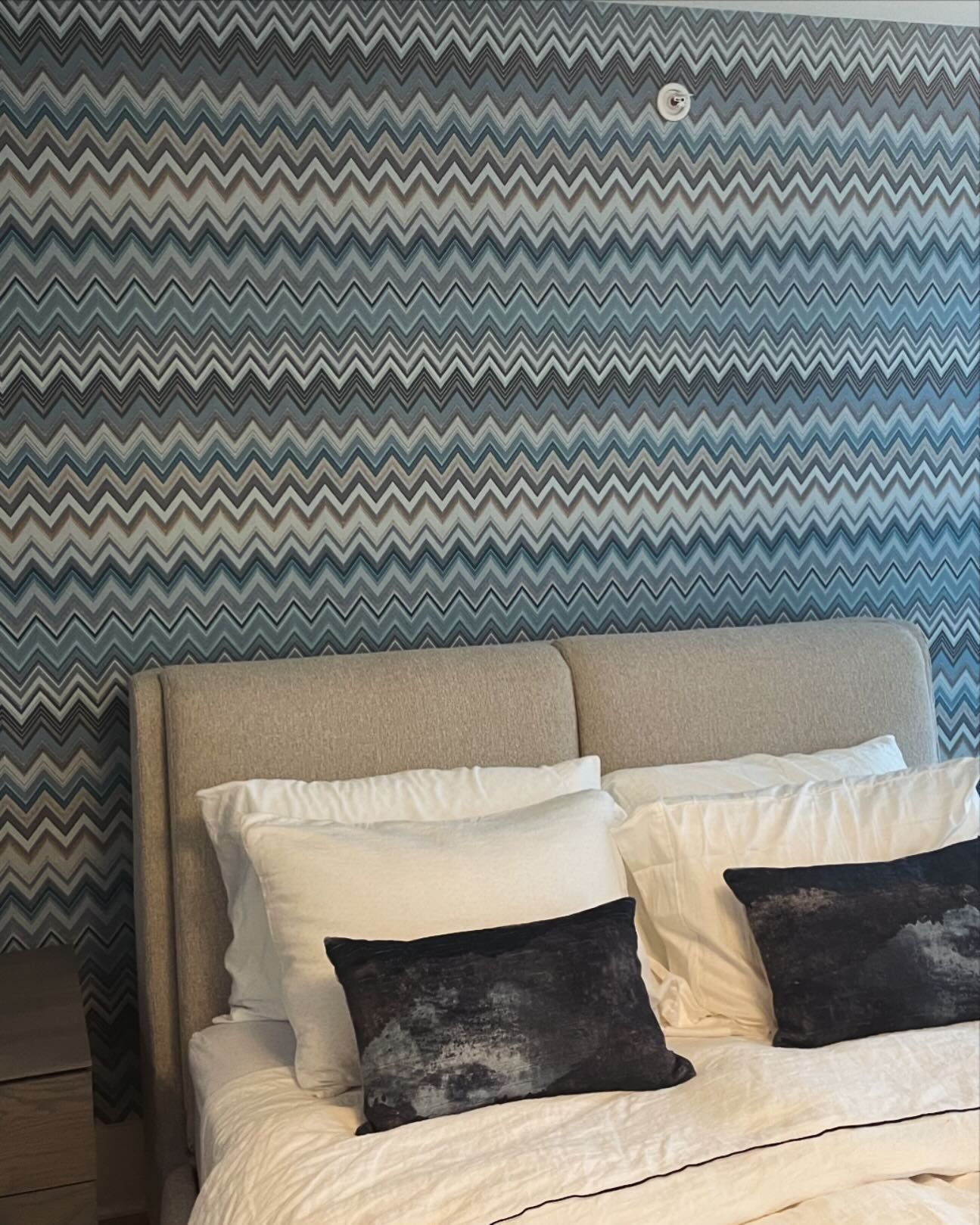 A bed with a chevron patterned wall behind it