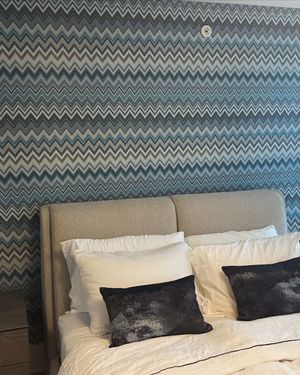 A bed with a chevron patterned wall behind it