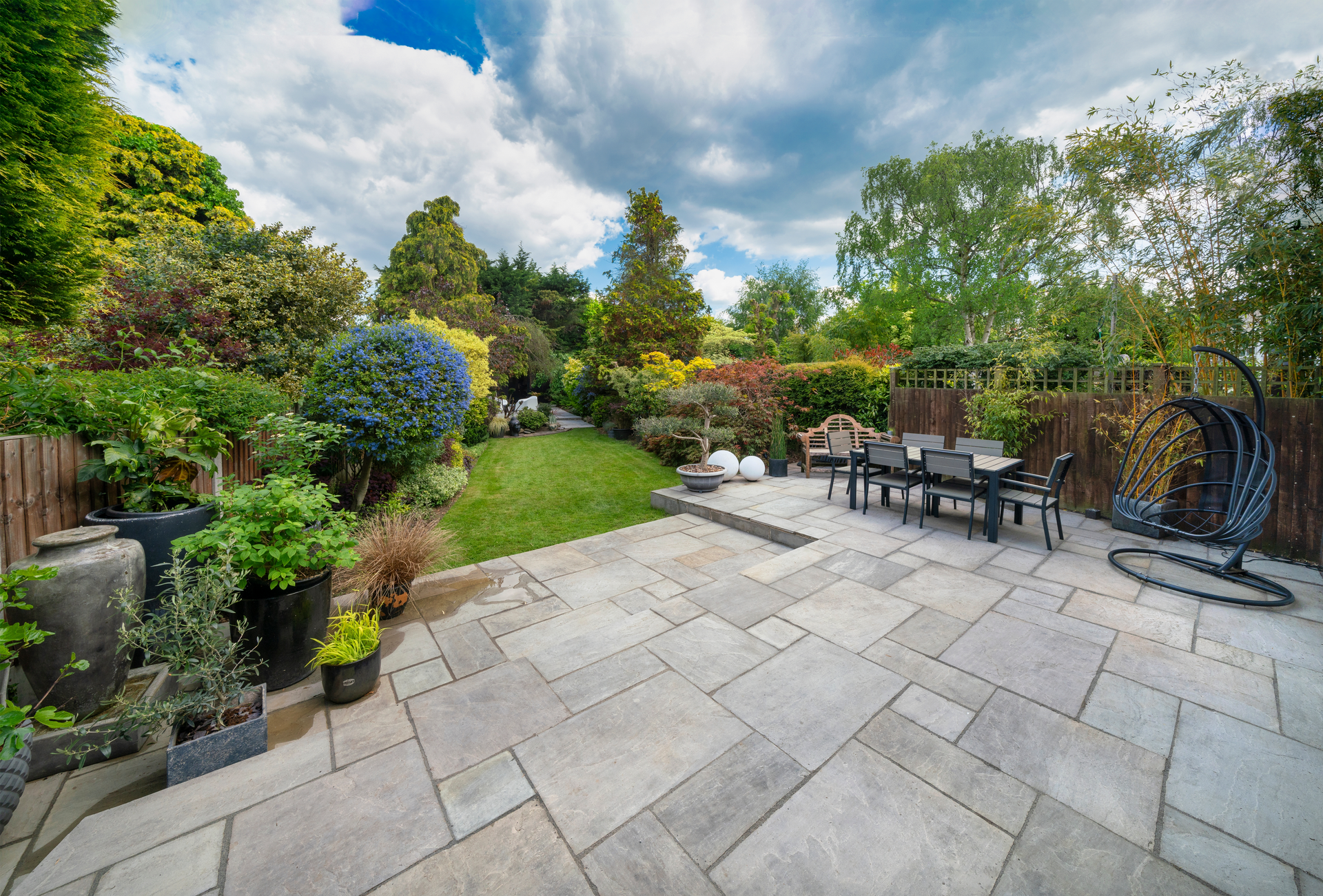 Beautiful summer garden in England, UK with lawn and large, indian sandstone patio.