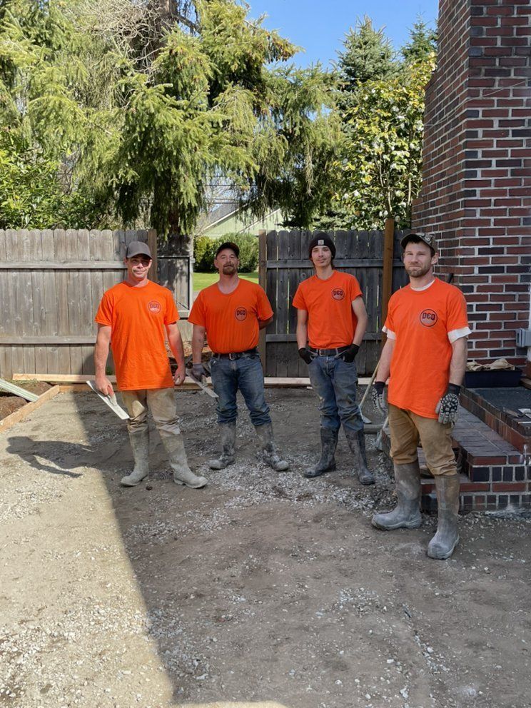 A group of construction workers are standing in front of a brick wall.