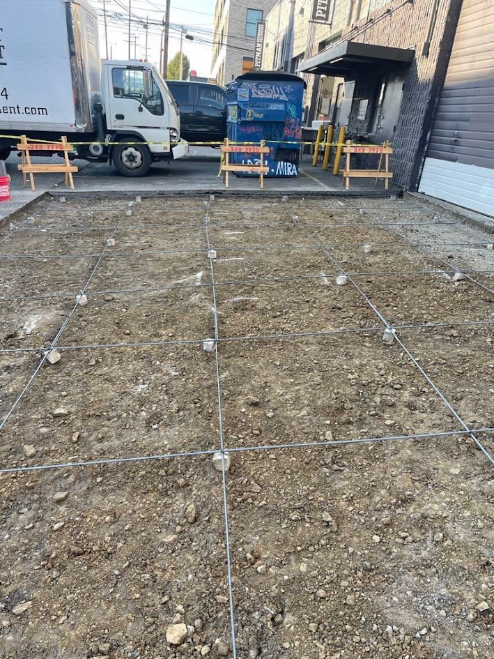 A white truck is parked in a dirt lot next to a building.
