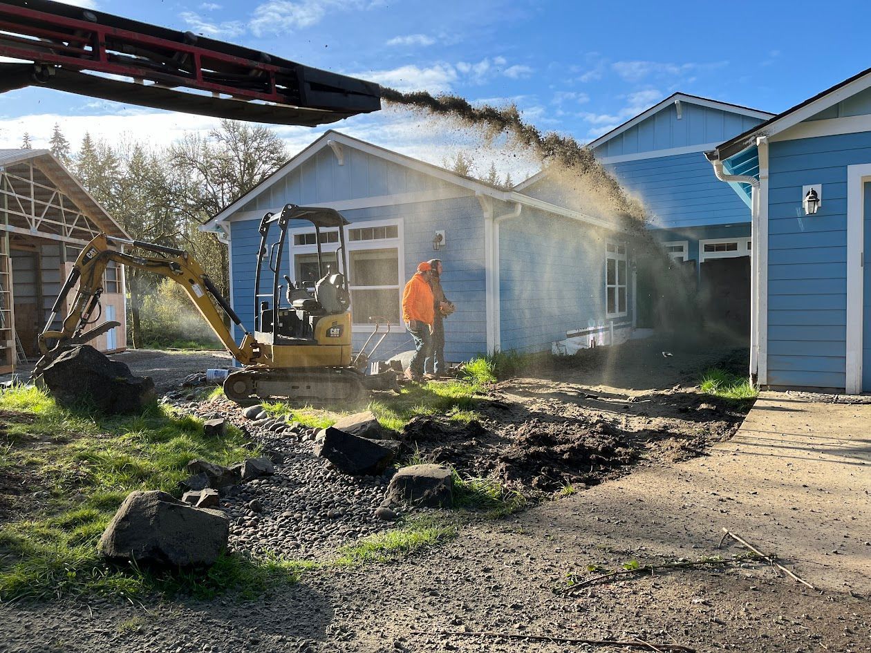 A man is standing in front of a house with a bulldozer.