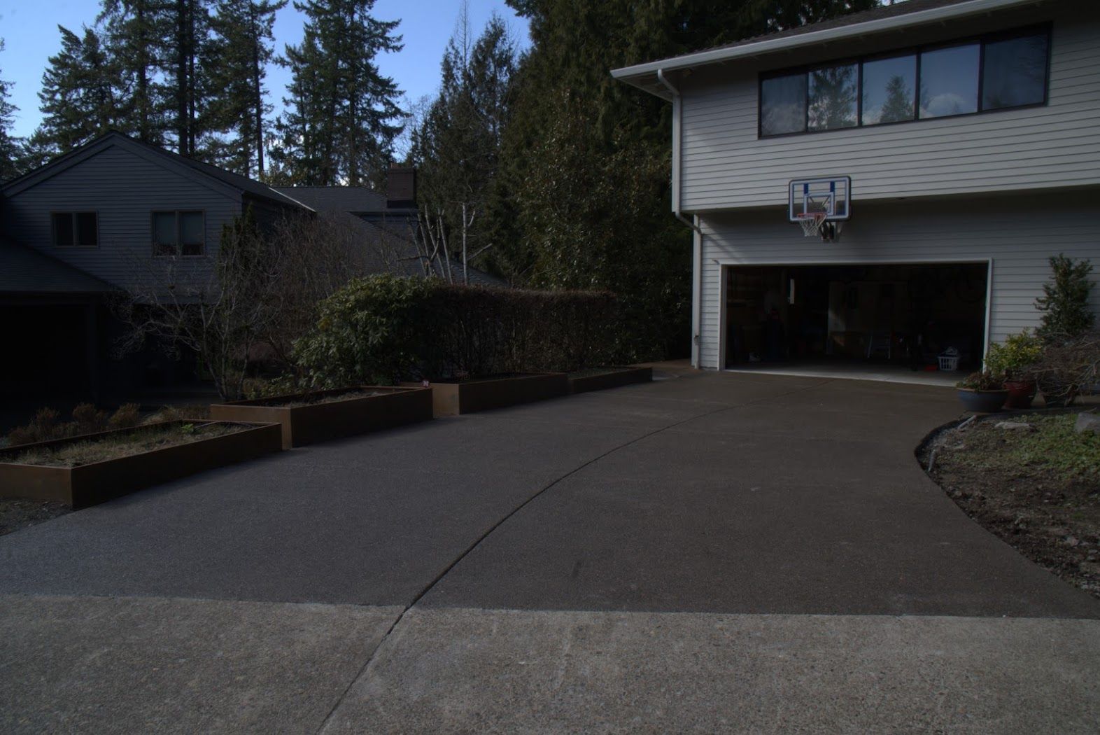 A driveway leading to a house with a garage and a basketball hoop
