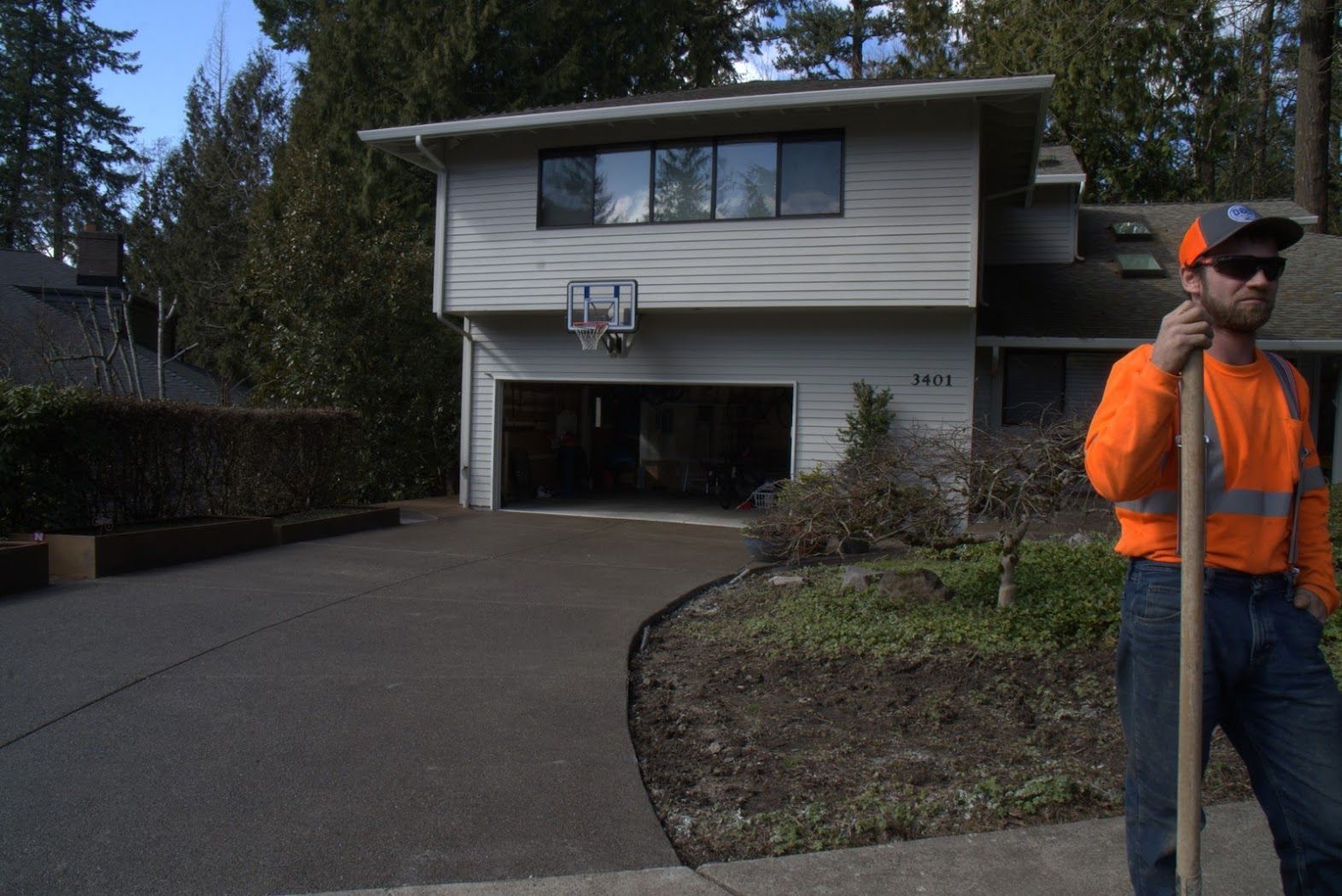 A man standing in front of a house holding a shovel