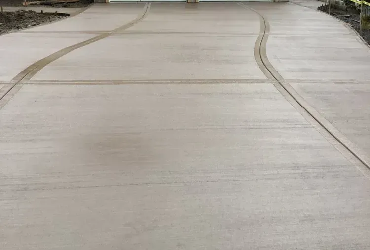 A concrete driveway with a curved path leading to a garage door.