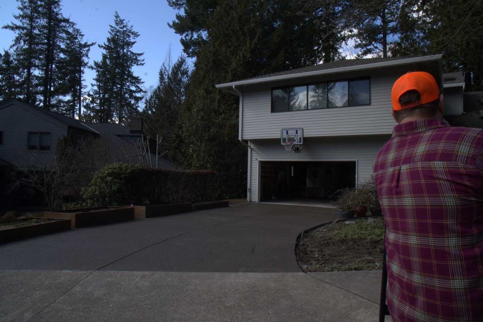 A man in an orange hat is standing in front of a house