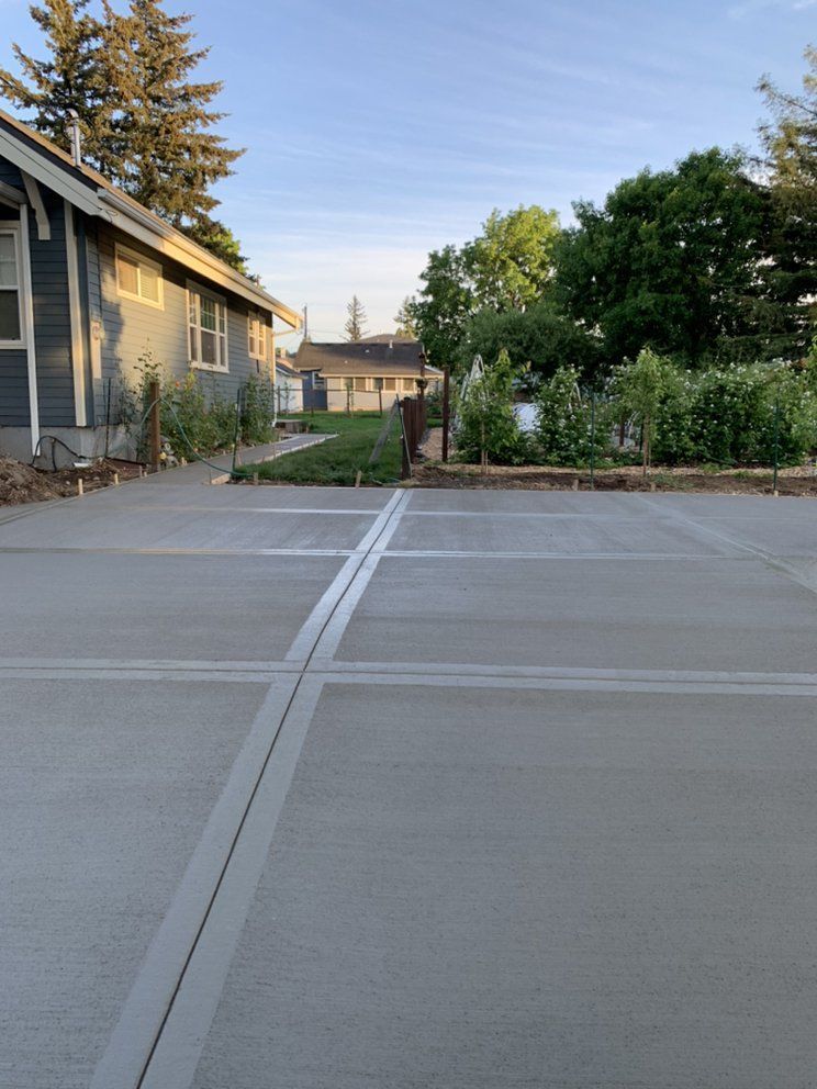A concrete driveway with a house in the background