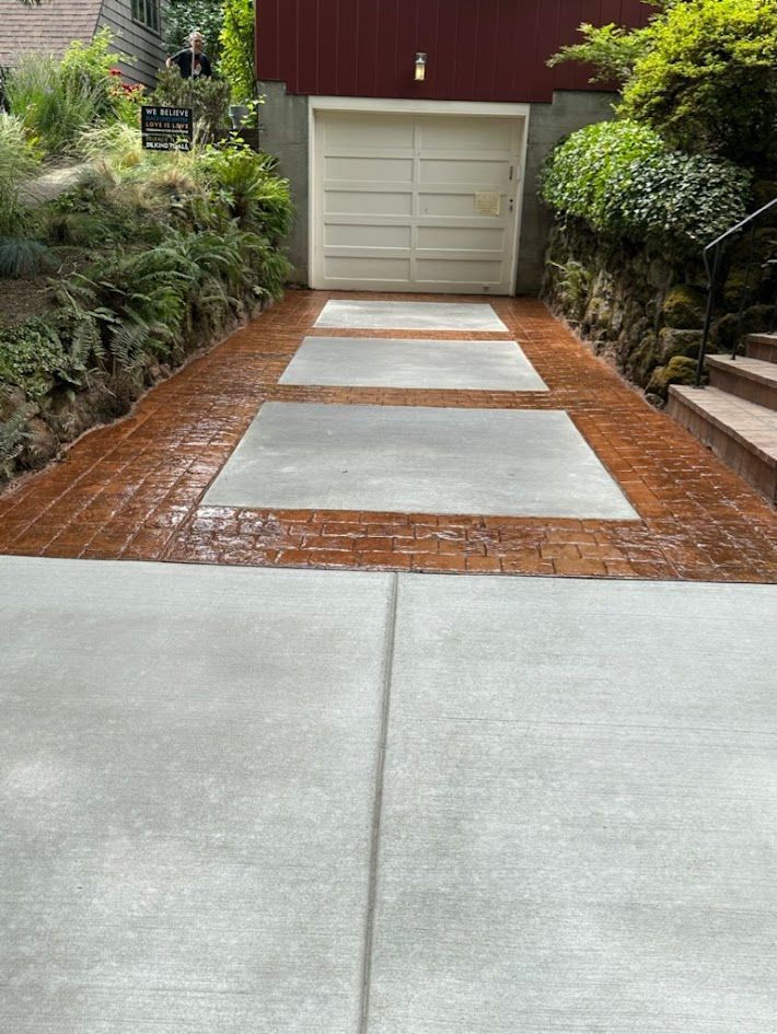 A concrete driveway leading to a garage with a brick border.