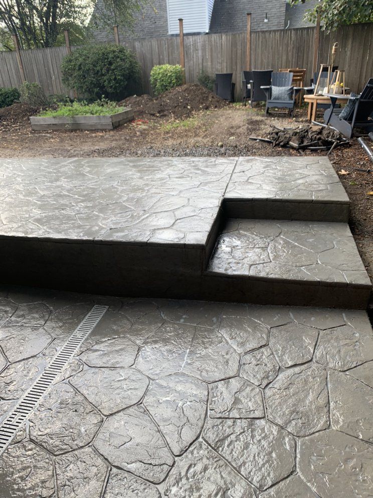 A concrete patio with steps and a fire pit in the backyard.