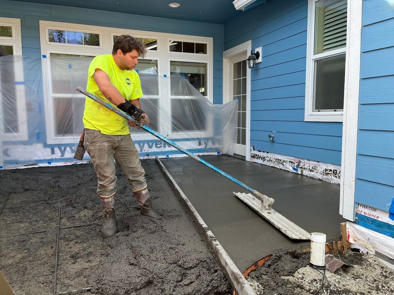 A man is spreading concrete on a porch with a mop.