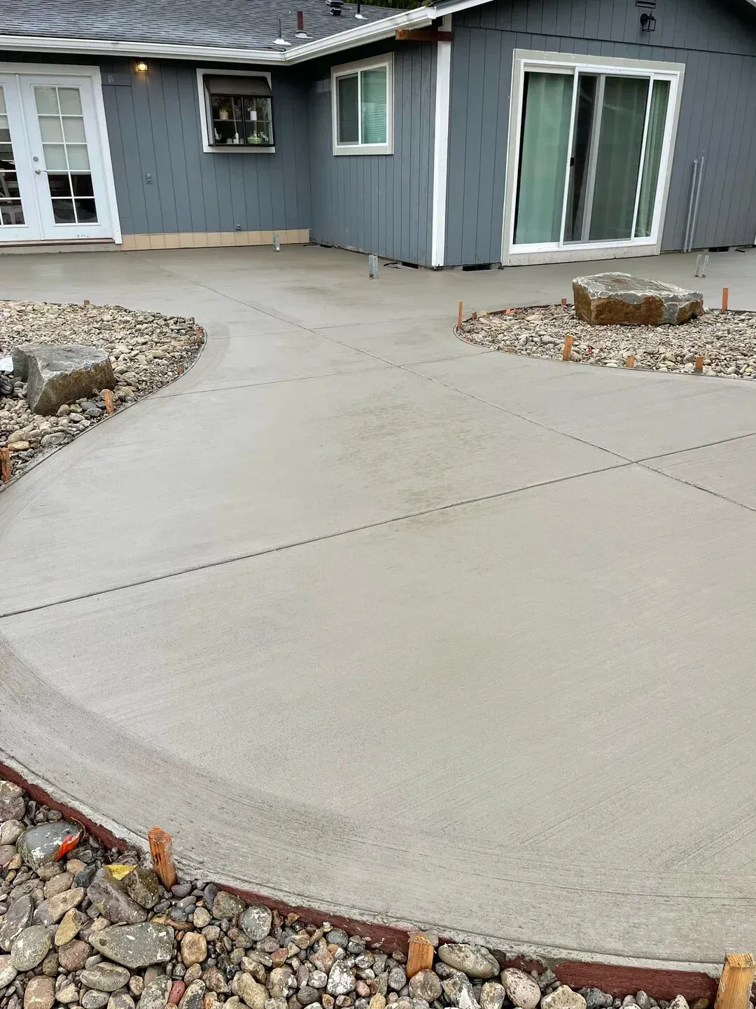 A concrete walkway leading to a house with a sliding glass door.