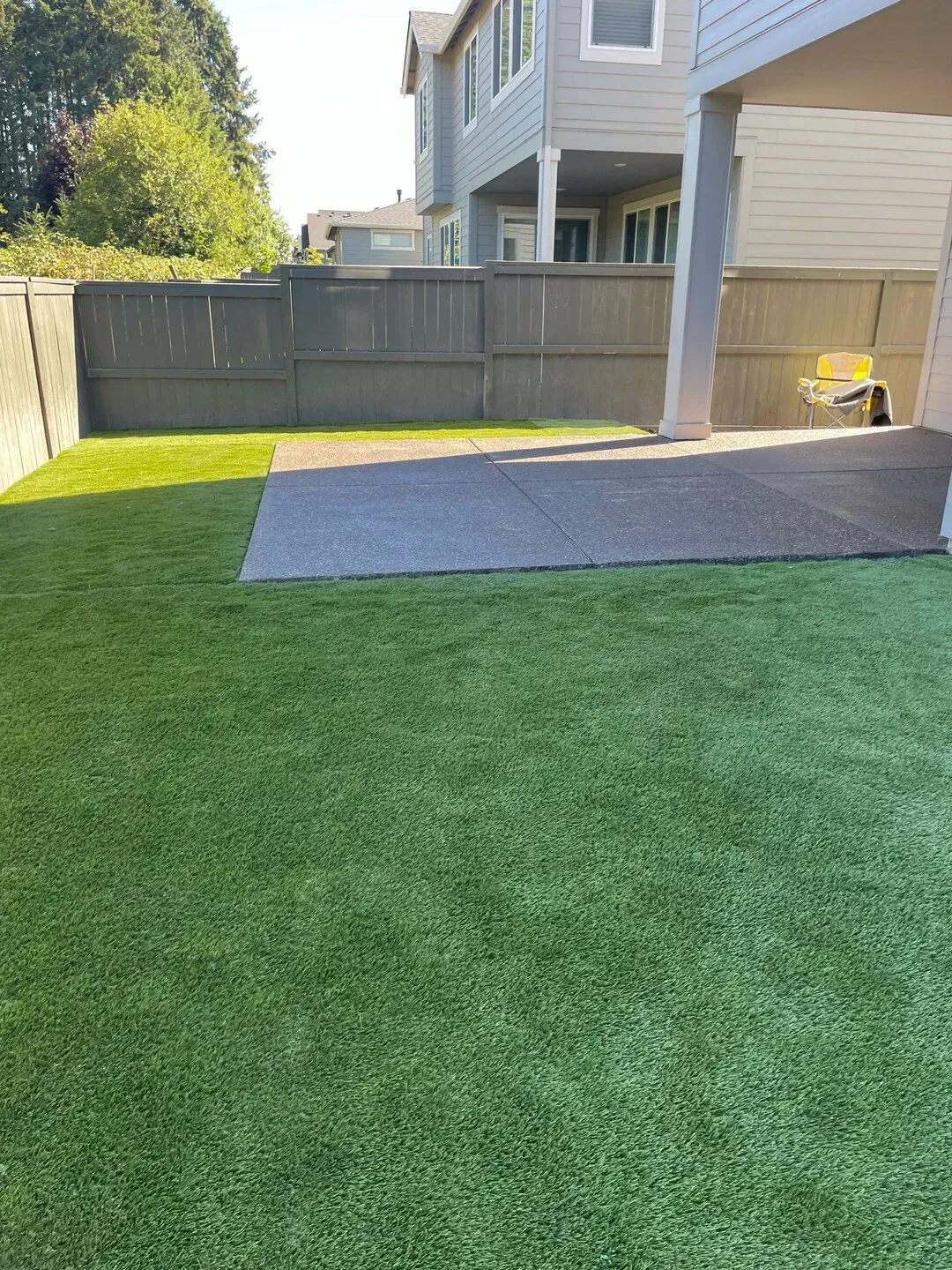 A backyard with a lot of grass and a house in the background.