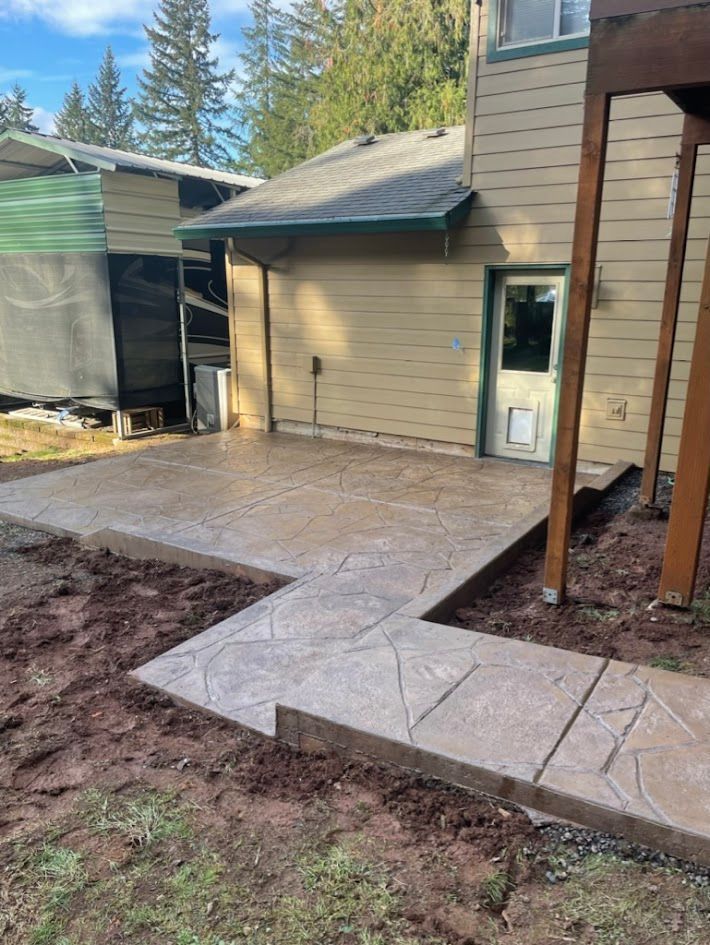 A concrete walkway leading to a house with a dog door.
