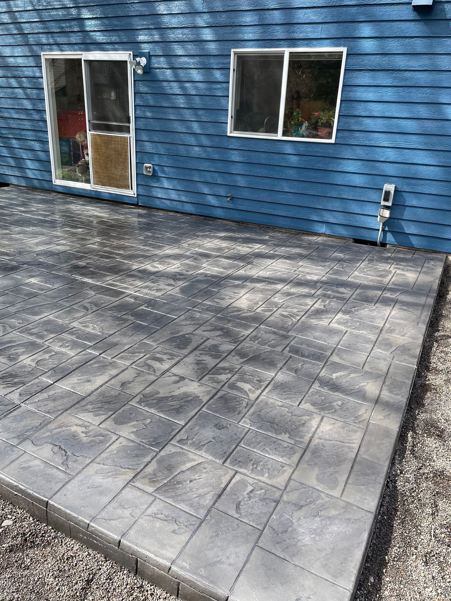 A blue house with a concrete patio in front of it.