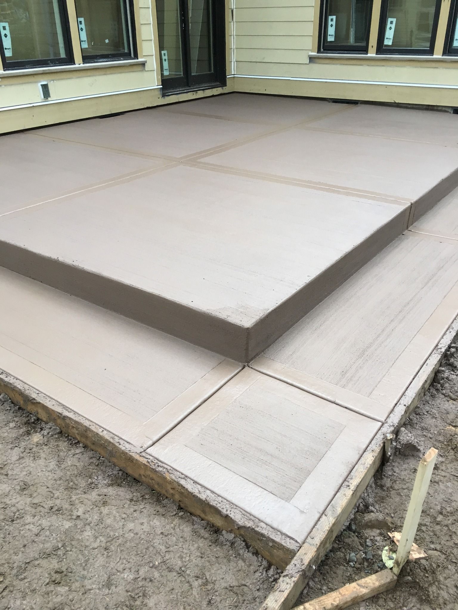A concrete patio is being built in front of a house.