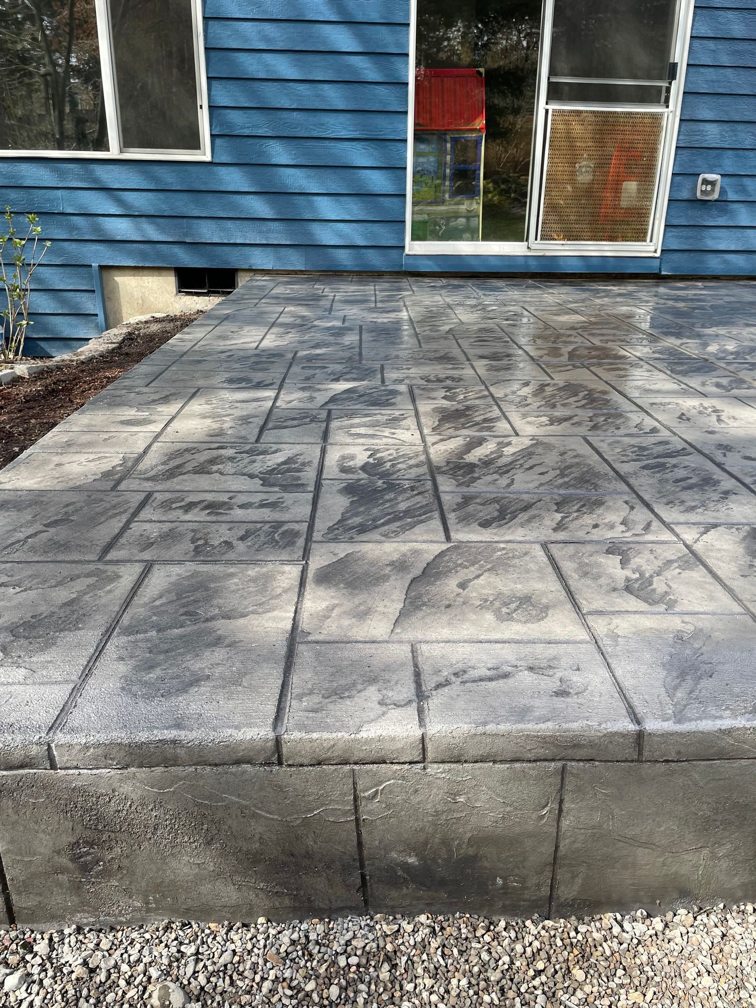 A blue house with a concrete patio in front of it.