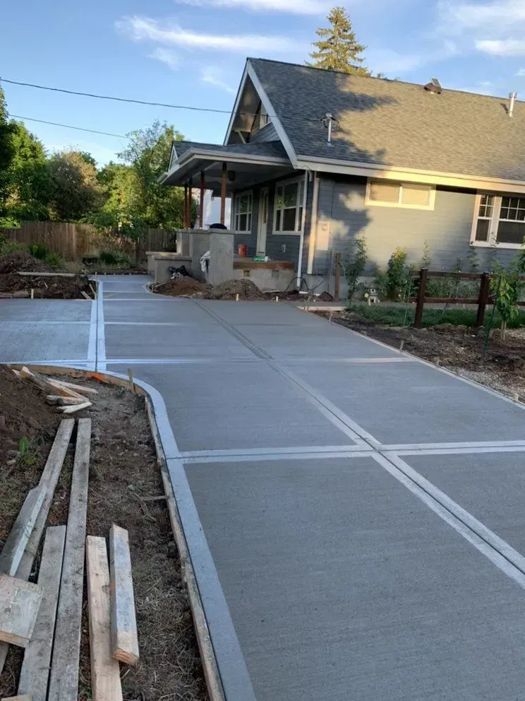A concrete driveway is being built in front of a house.
