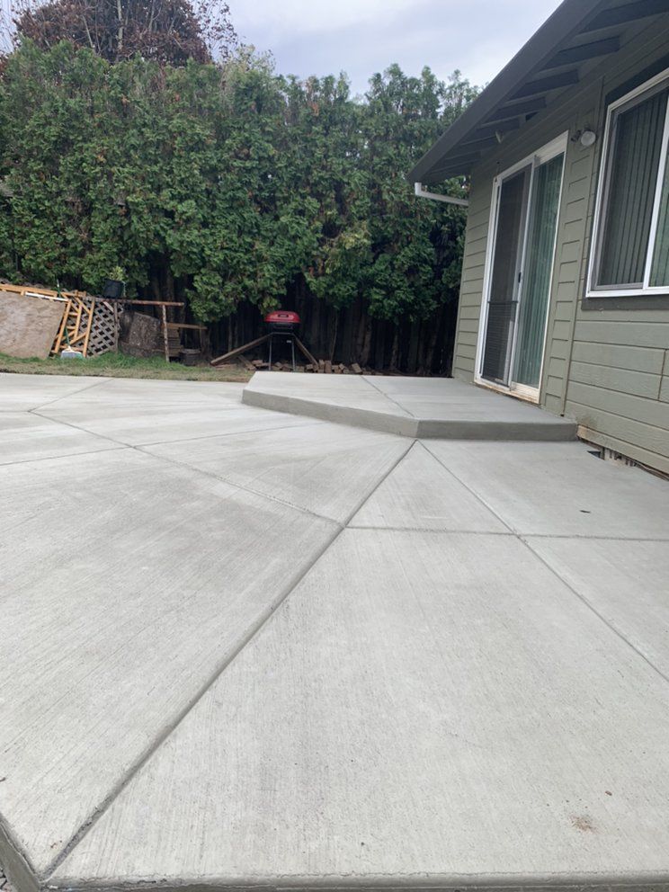 A concrete patio in front of a house with a sliding glass door.