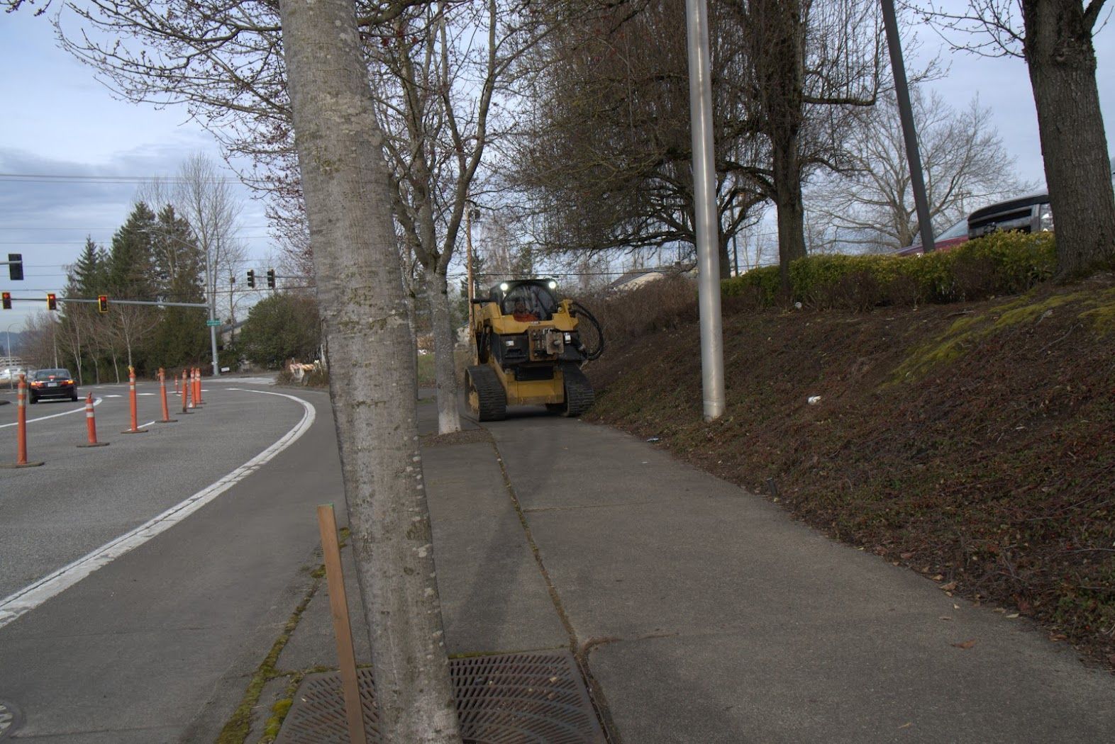 A forklift is driving down a sidewalk next to a street.