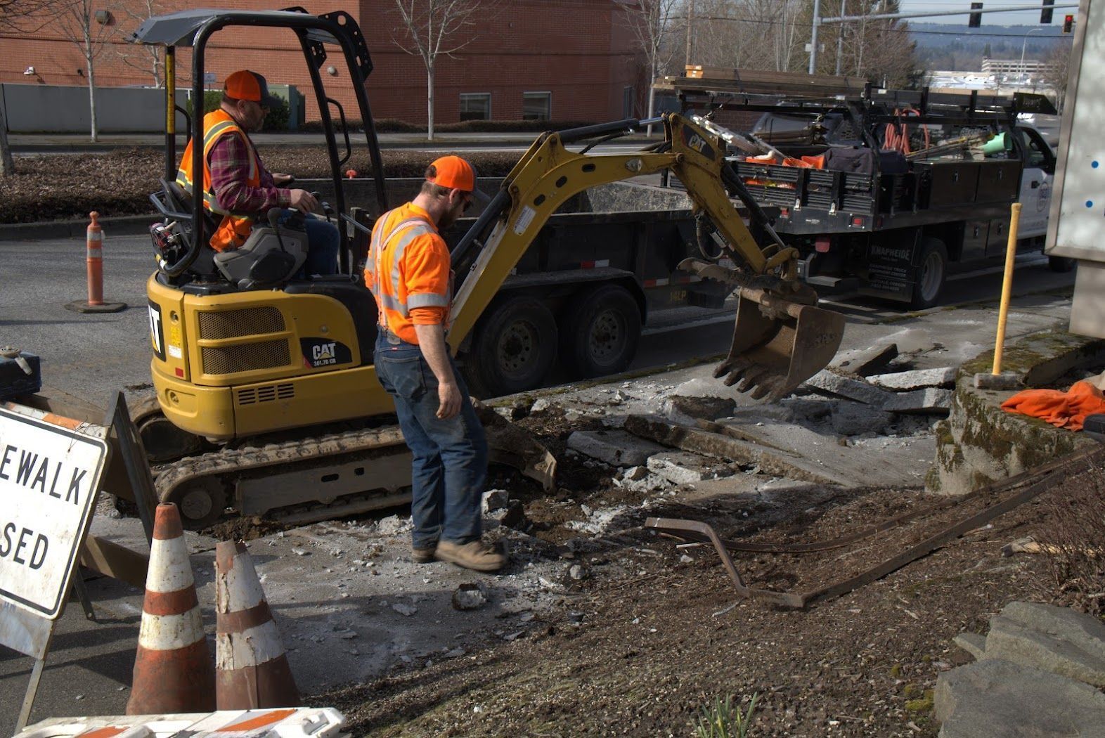 A man is standing next to a yellow excavator.
