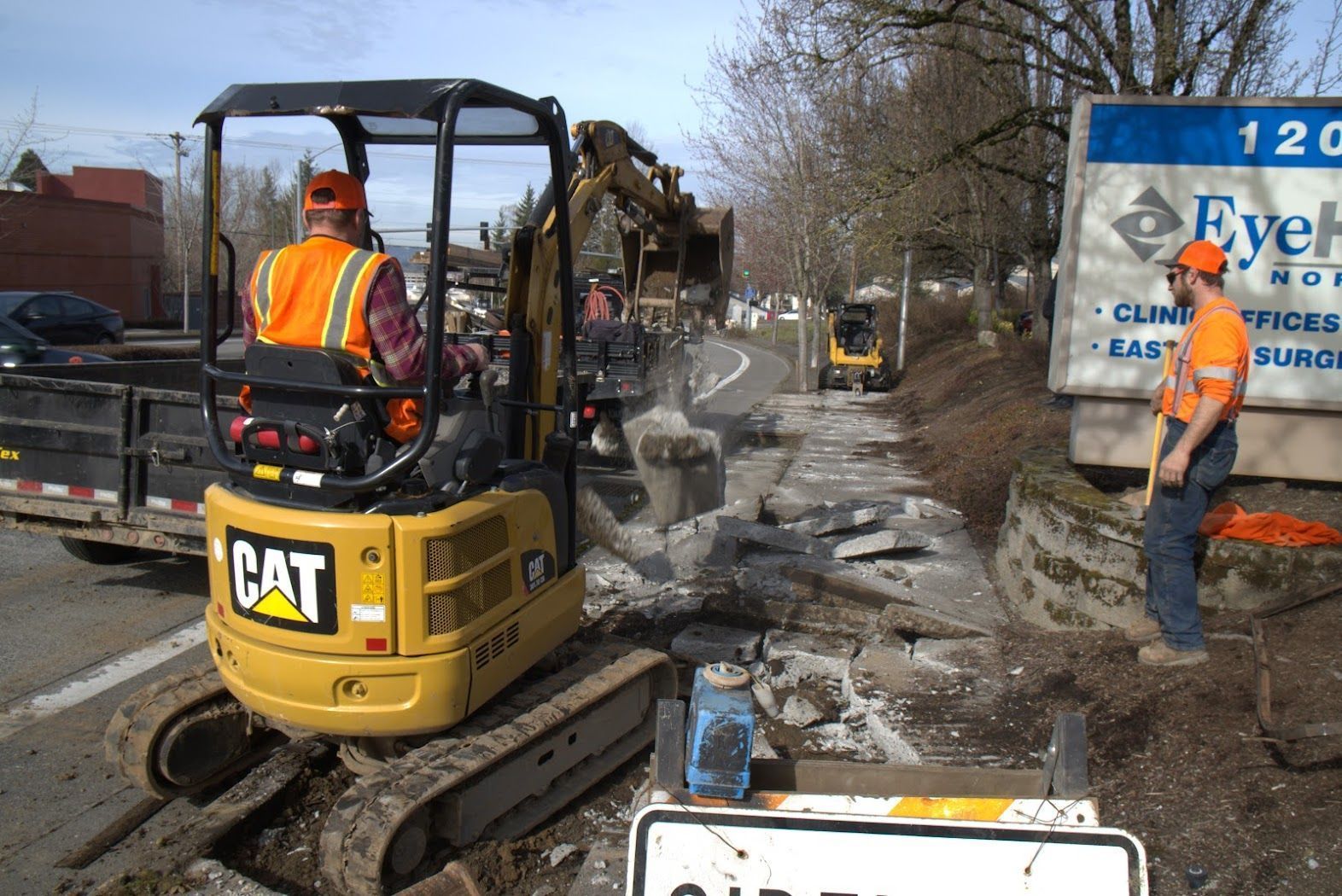 A man is standing next to a cat excavator