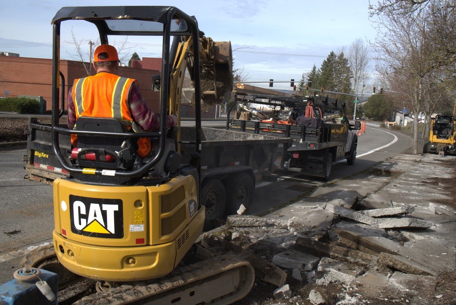 A man is driving a cat excavator on a street.