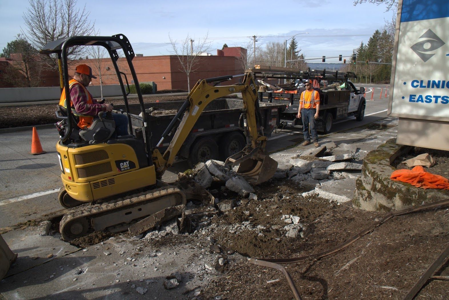 A man is driving a yellow excavator on a street