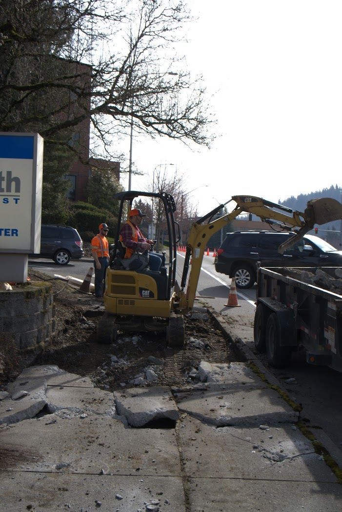 A man is driving a yellow excavator next to a sign that says health