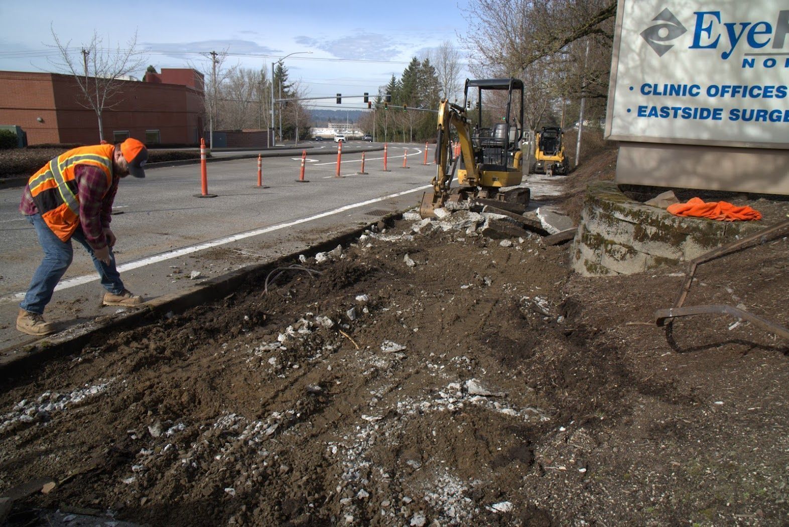 A man is digging in the dirt in front of an eye hospital sign.