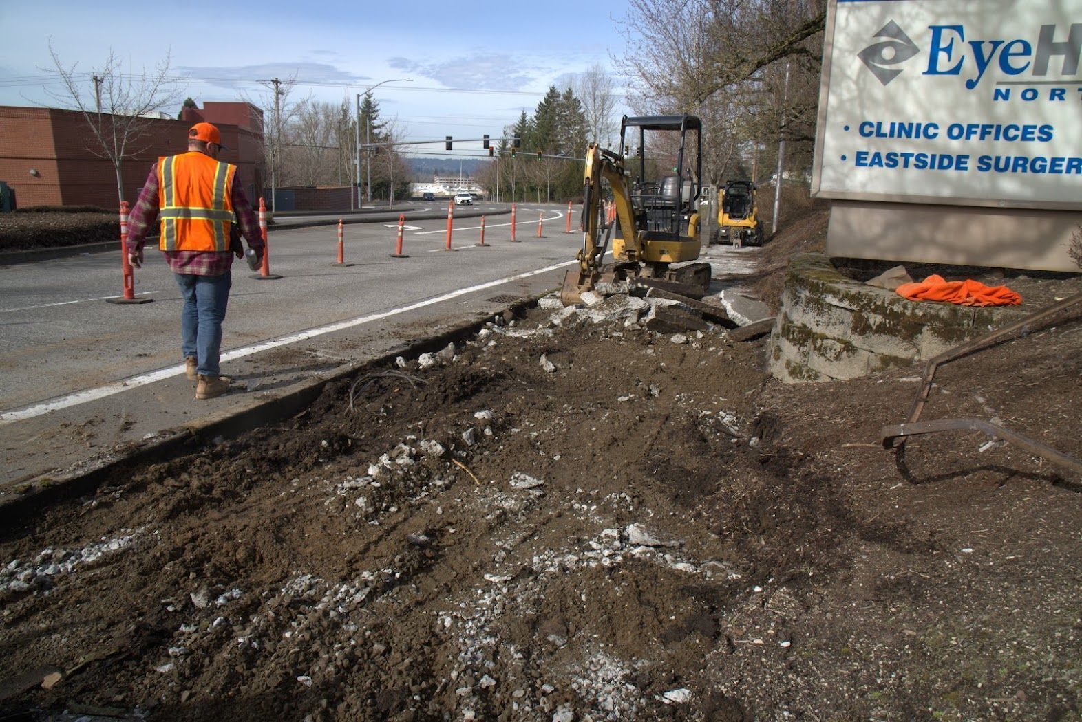 A construction worker walks past a sign that says eye hospital