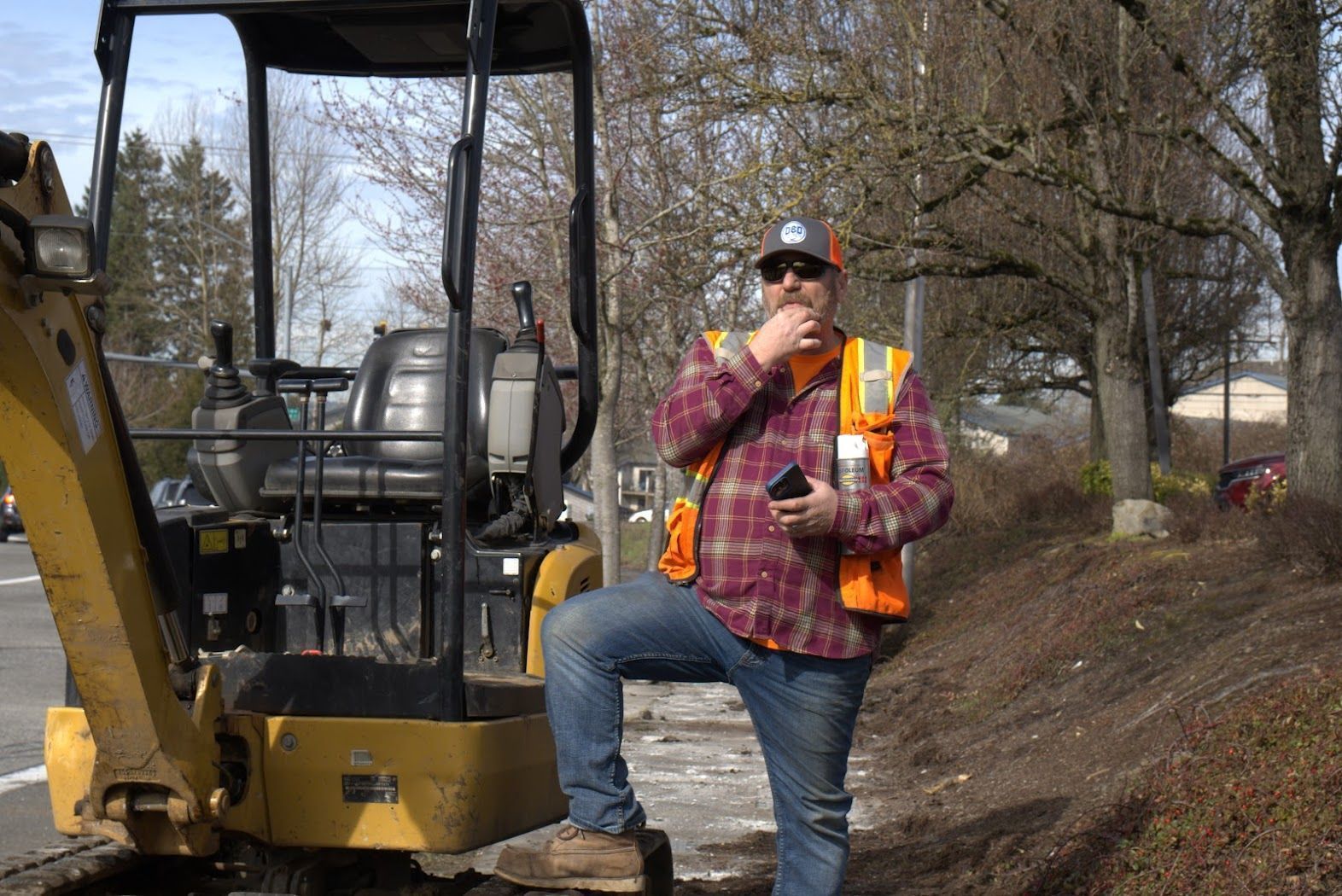 A man is kneeling on the back of a small excavator.
