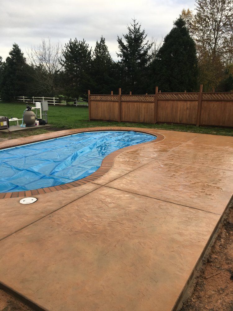 There is a swimming pool in the backyard with a wooden fence.
