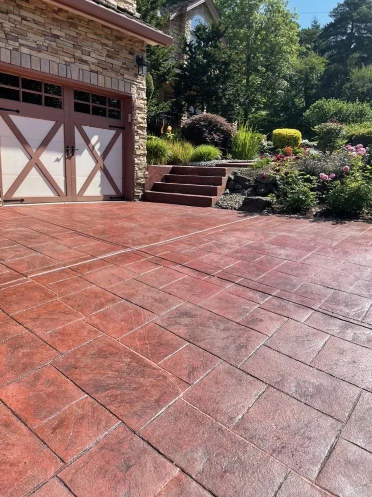 A red brick driveway in front of a garage with stairs leading up to it.