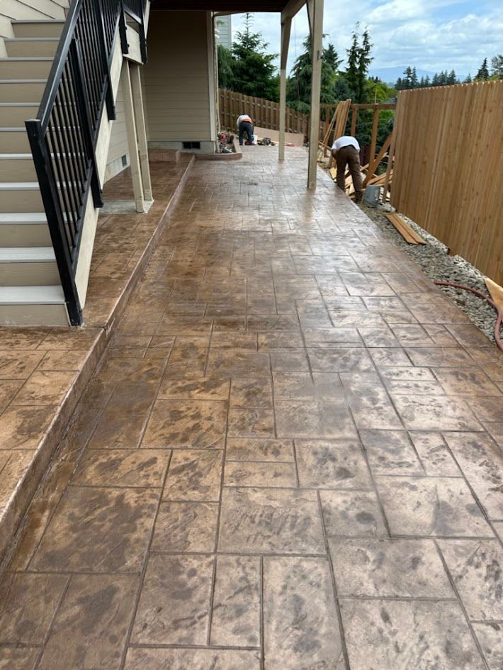 A concrete walkway with stairs and a fence in the background.