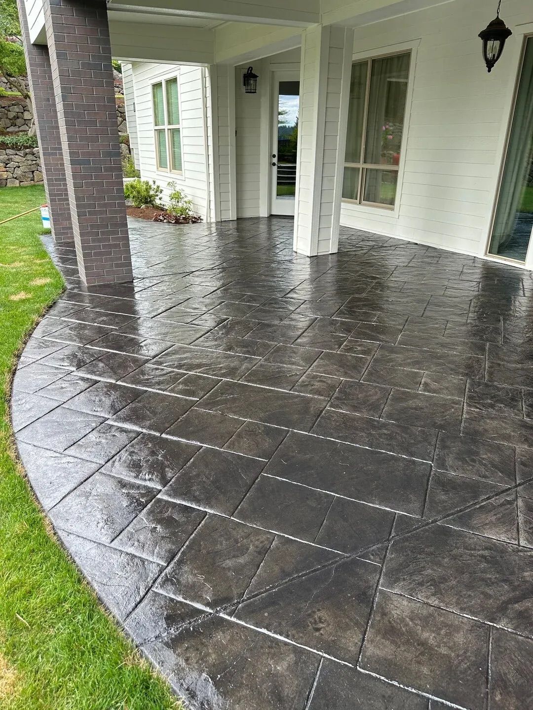 A black concrete patio with a white house in the background.