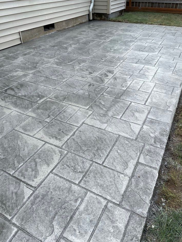 A gray concrete patio with a house in the background.