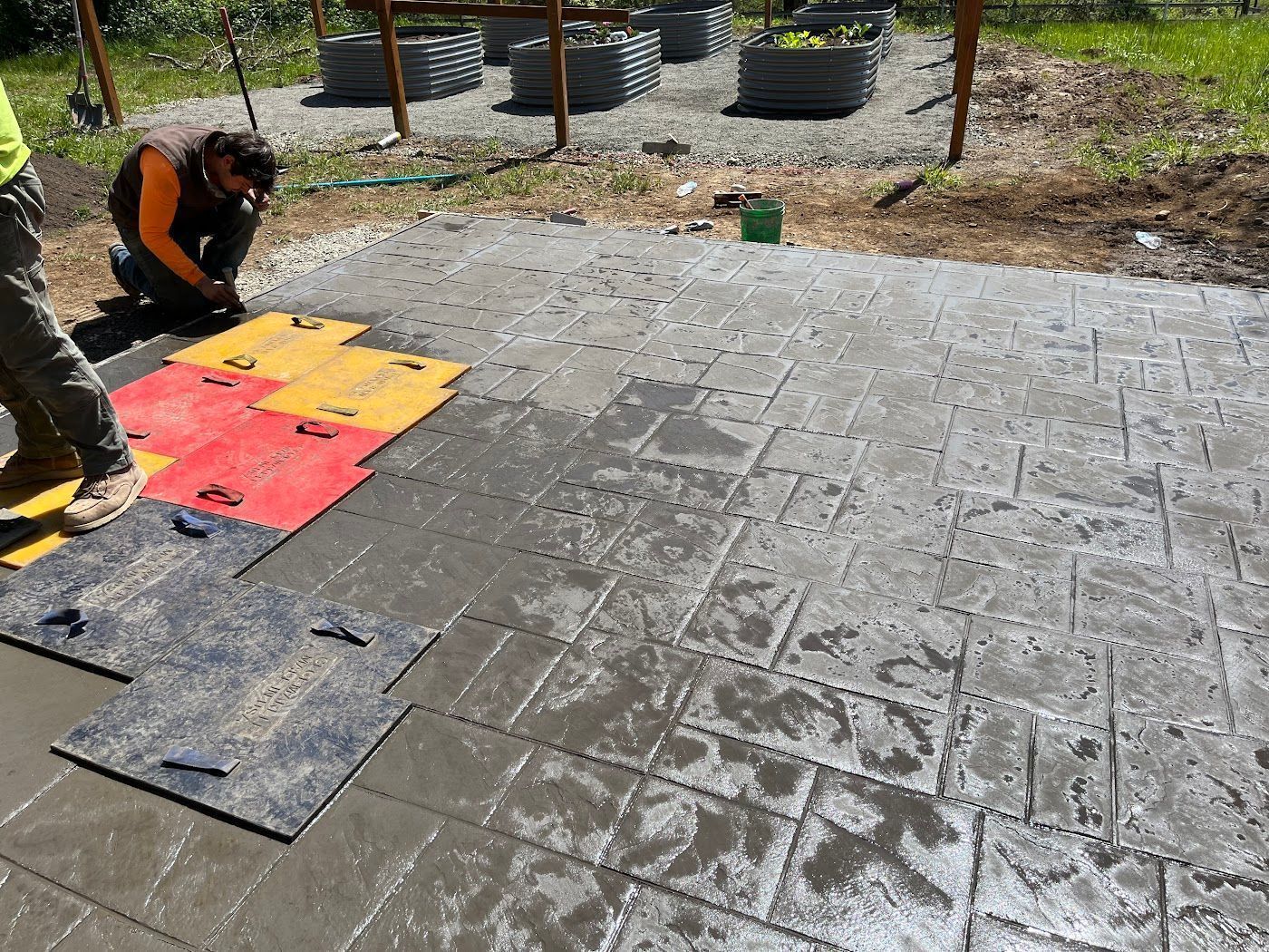 A man is laying concrete on a patio.