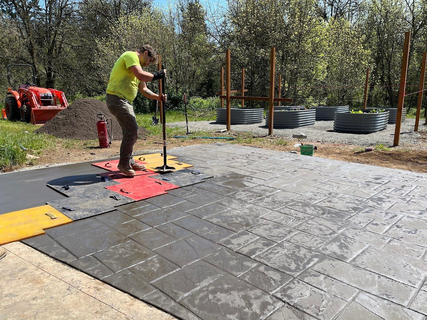 A man is working on a concrete driveway with a hammer.