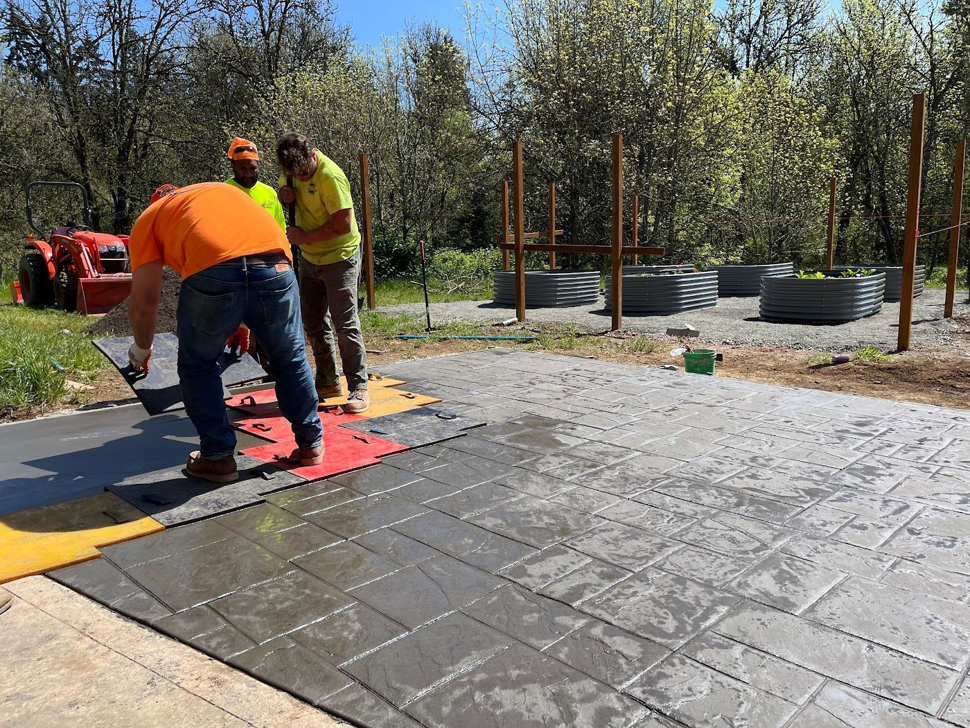 A group of men are working on a concrete driveway.