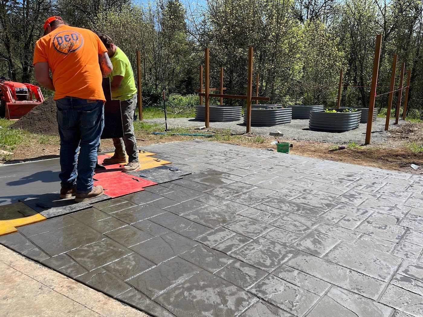 A group of men are working on a concrete driveway.