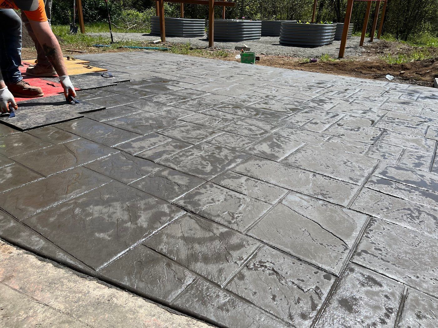 A man is laying concrete tiles on a patio.