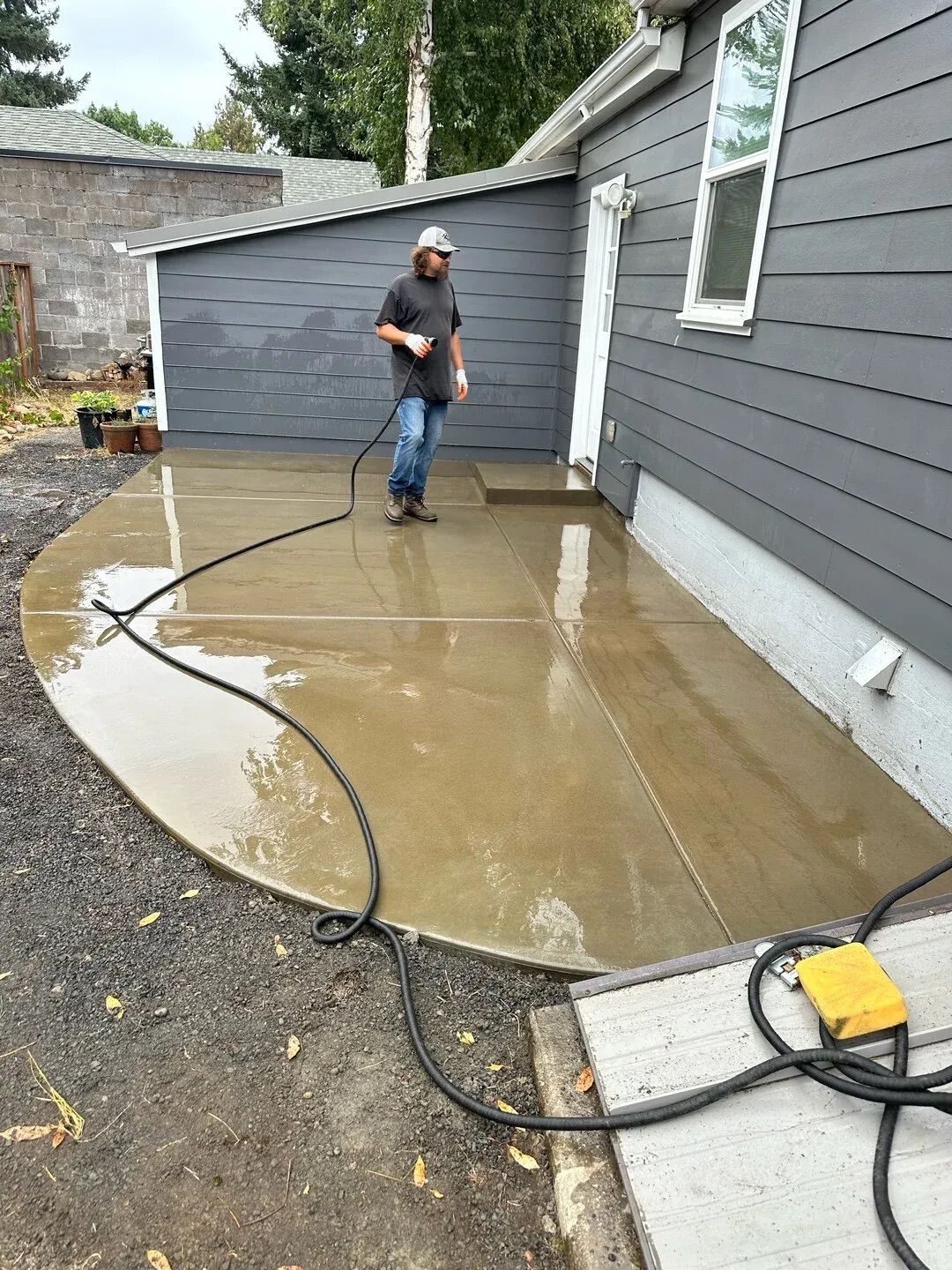 A man is cleaning a concrete patio with a pressure washer.