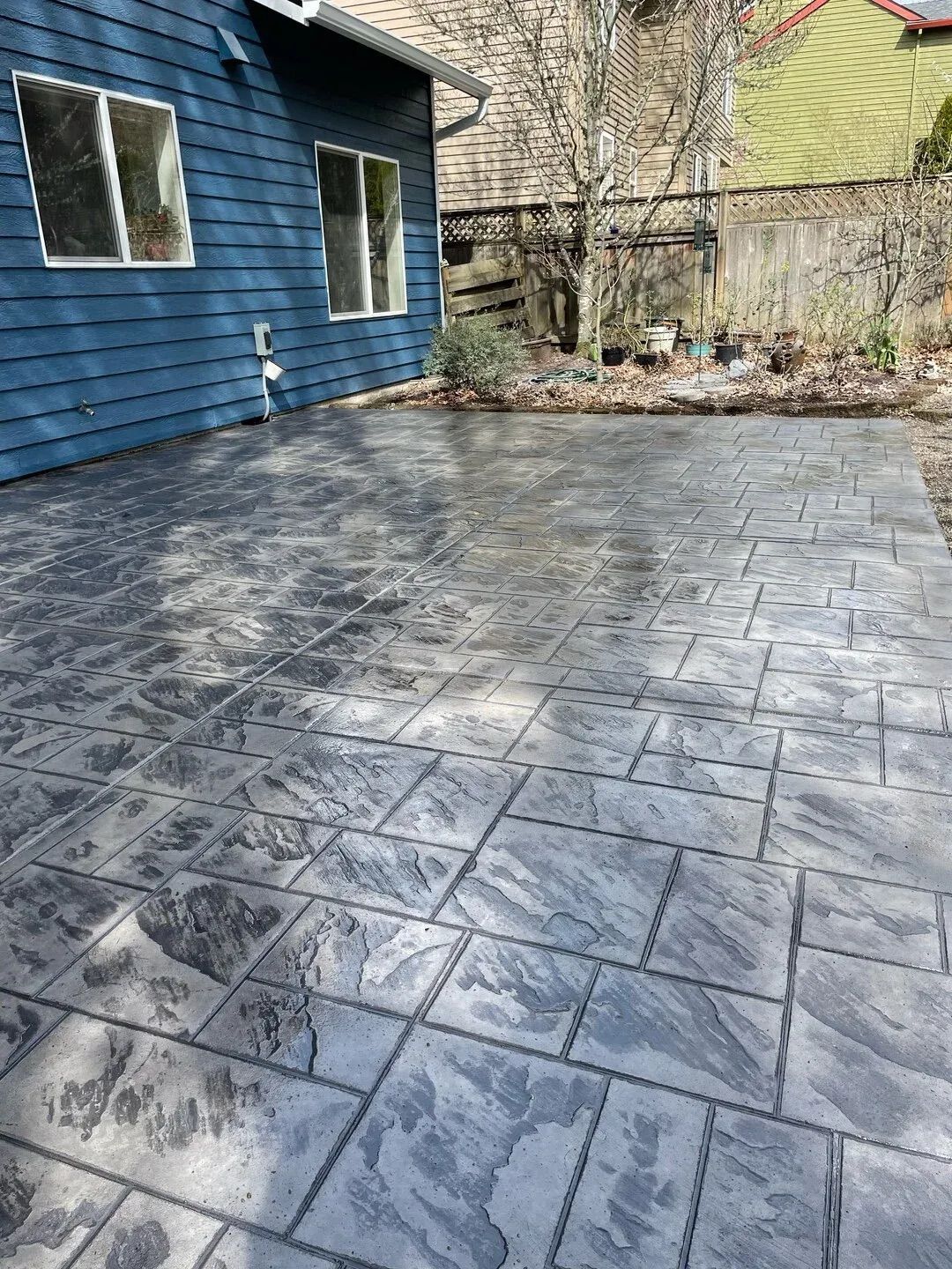 A concrete patio with a blue house in the background.