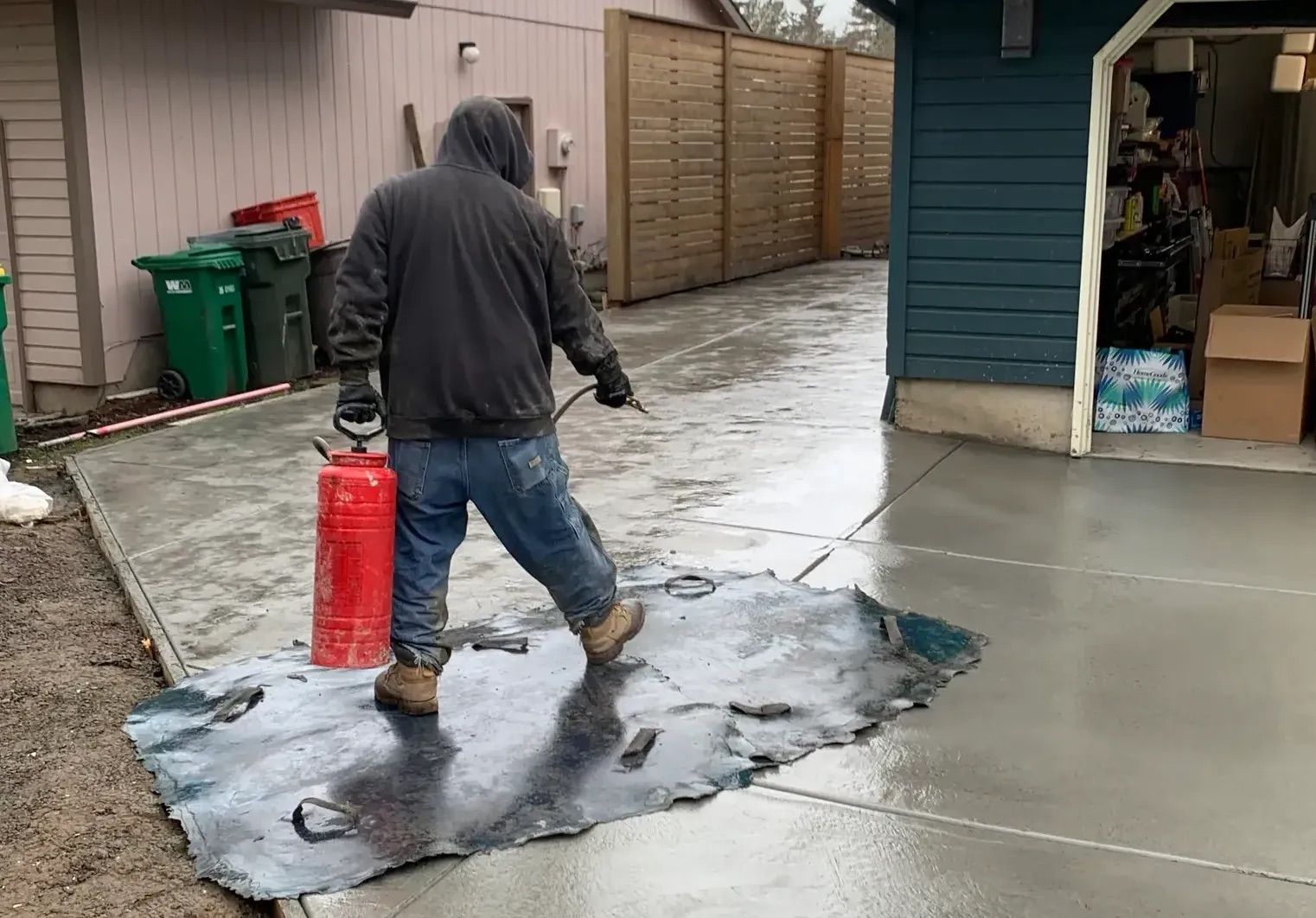 A man is spraying a concrete driveway with a fire extinguisher.
