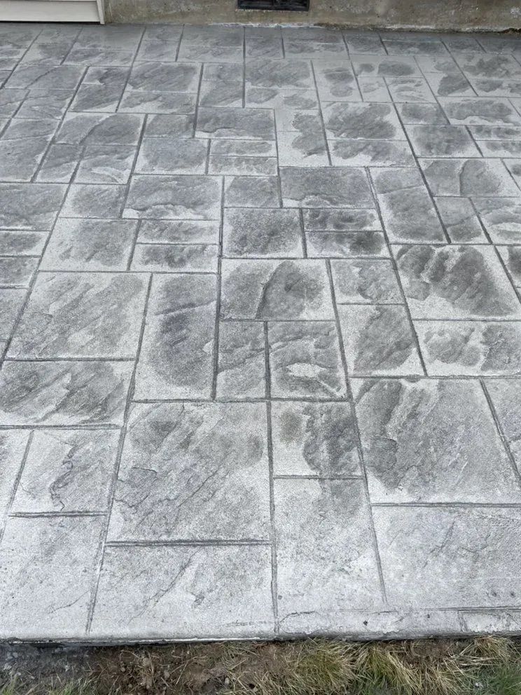A close up of a concrete patio with a brick pattern.