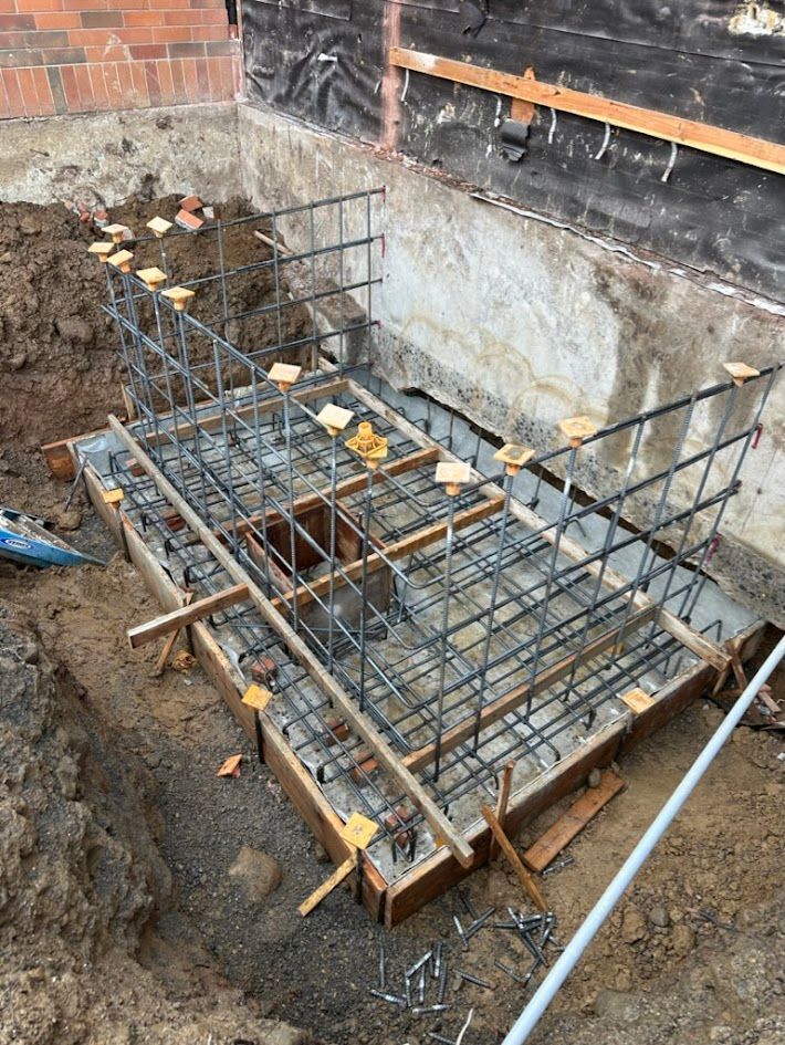 A concrete base is being built in a hole in the ground.