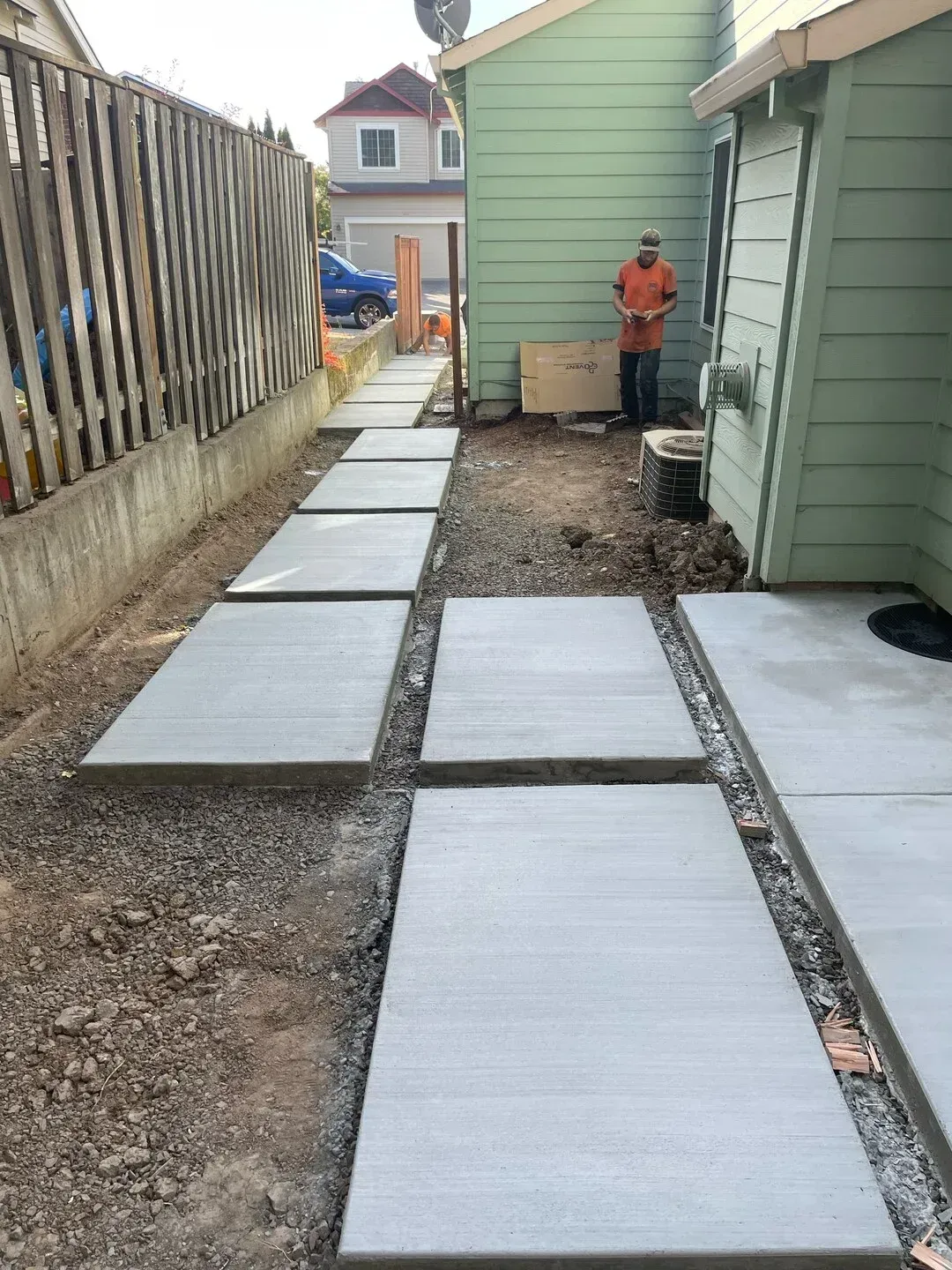 A concrete walkway is being built in front of a green house.