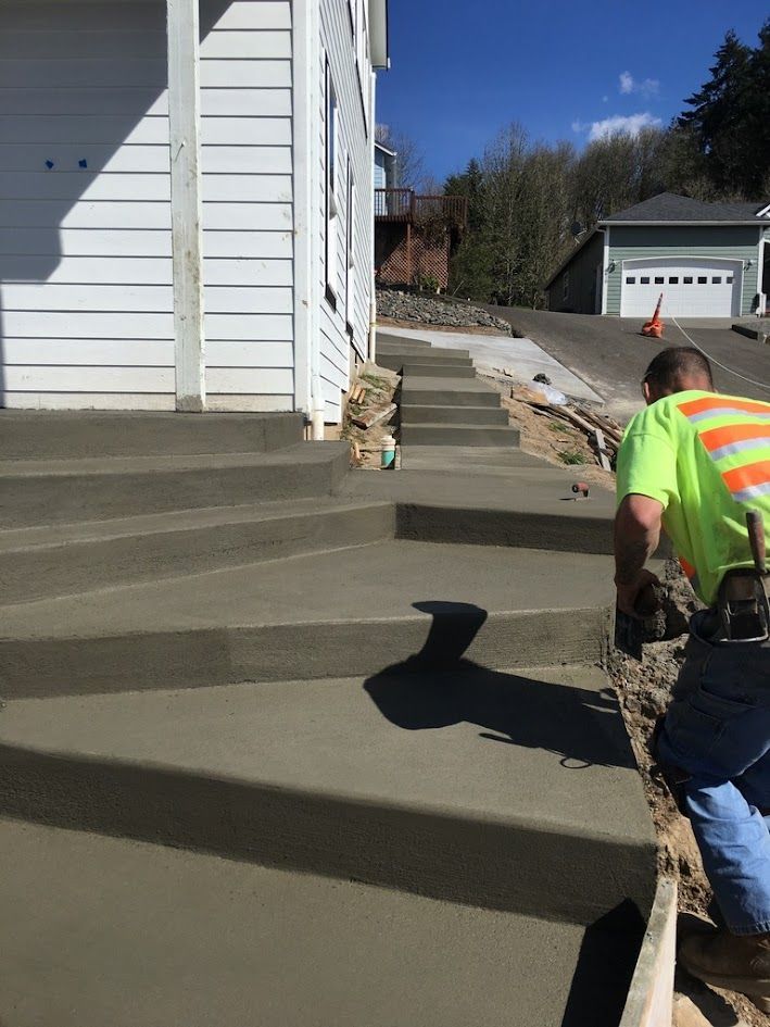 A man is working on concrete steps in front of a house